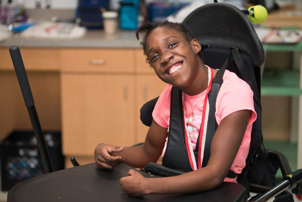 A young girl with a big smile staring at the viewer.