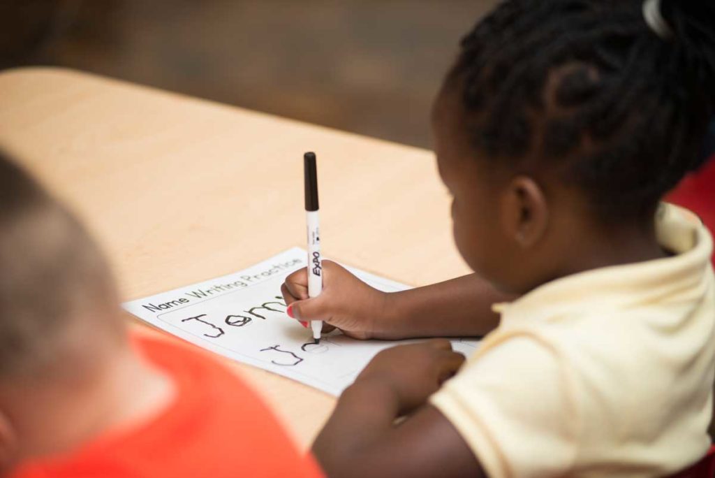 A girl practices writing with a black pen.