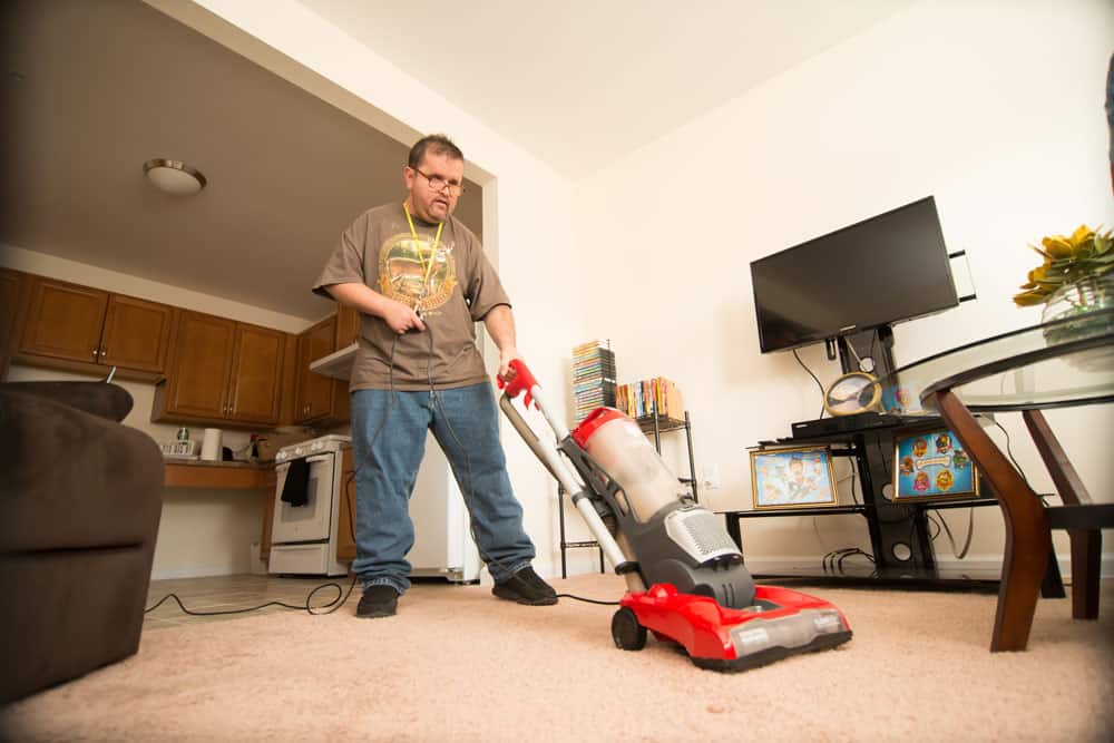 A man vacuums in a living room.